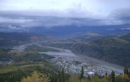 A river in a valley with birds eye view of a town on the left side