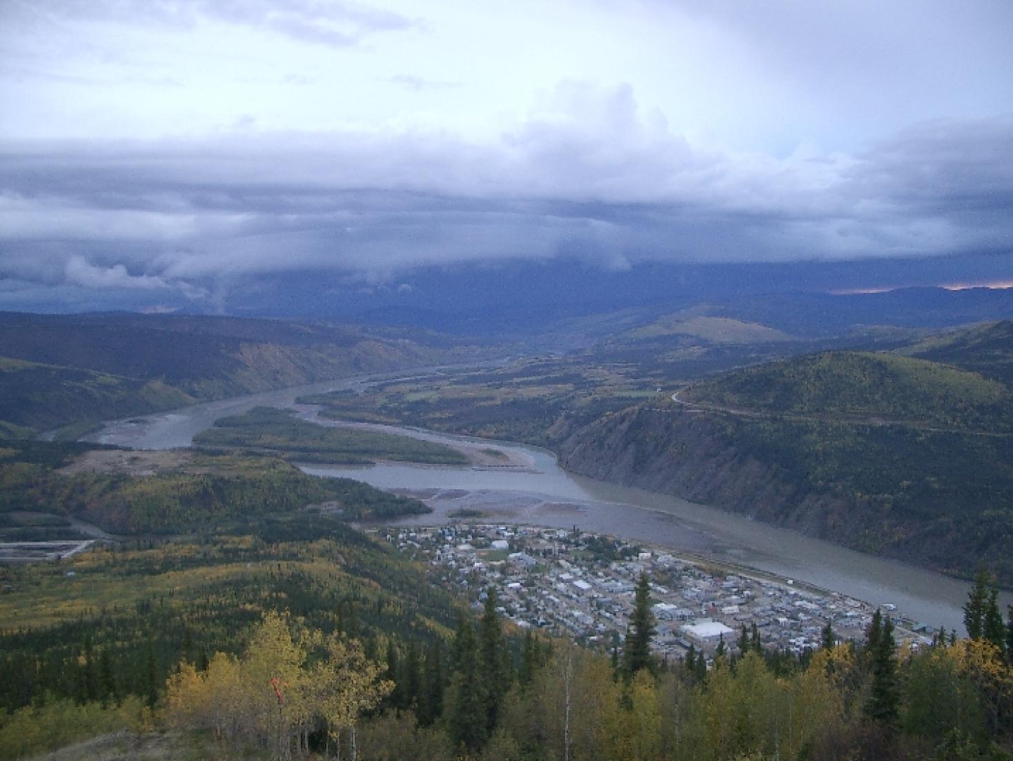 A river in a valley with birds eye view of a town on the left side